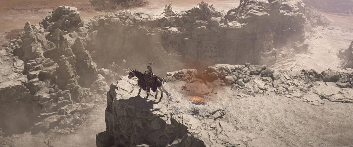 Un cavalier sur un éperon rocheux domine un canyon désertique et brumeux dans Diablo IV