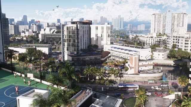 Quartier de Vice City en plein jour : hôtels Art déco, palmiers, terrain de basket et gratte-ciel au fond