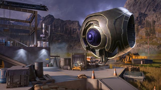 Un robot sphérique flotte au-dessus d'une base militaire au pied de montagnes dans Halo Infinite