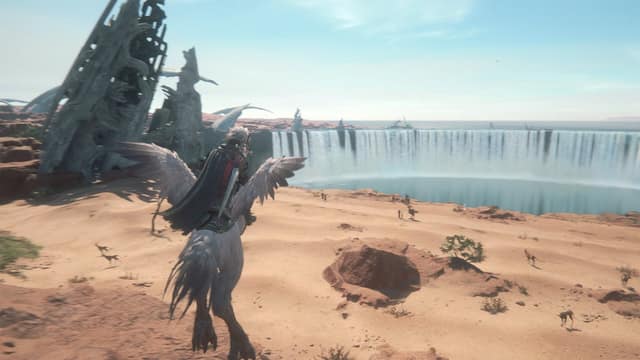 Clive chevauche un chocobo dans un désert, face à une immense cascade, dans Final Fantasy XVI
