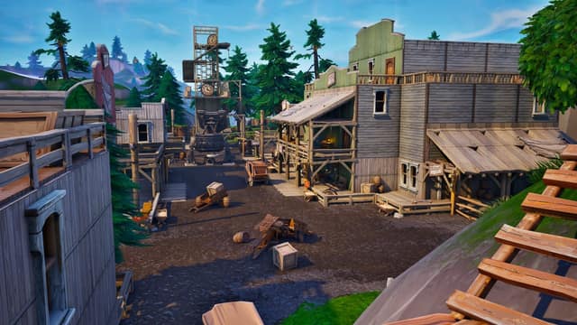 Rue en terre bordée de maisons en bois et de sapins sur l'île de Fortnite OG