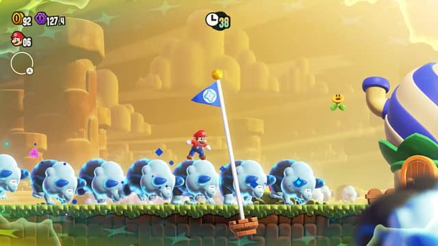 Mario, porté par un troupeau de créatures bleues, arrive au mât d'arrivée dans Super Mario Bros. Wonder