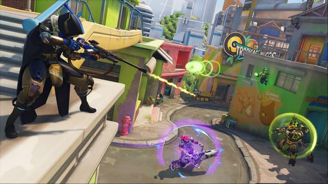 Une tireuse encapuchonnée couvre son équipe depuis une terrasse d'une ville colorée dans Overwatch