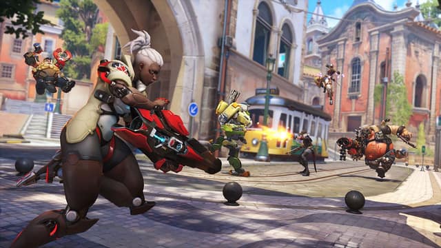 Une héroïne aux cheveux blancs charge son canon sur une place pavée bordée d'un tramway jaune dans Overwatch