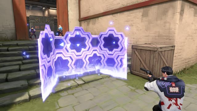 Un mur d'énergie violet aux motifs hexagonaux protège un agent accroupi derrière une caisse