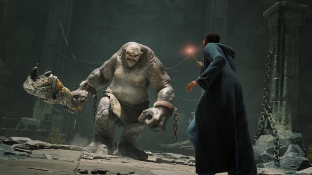 Un élève affronte à la baguette un troll enchaîné qui brandit une massue dans un souterrain