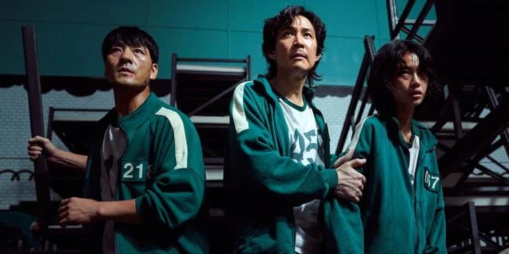 Squid Game : trois joueurs en survêtement vert dans le dortoir de la série Netflix