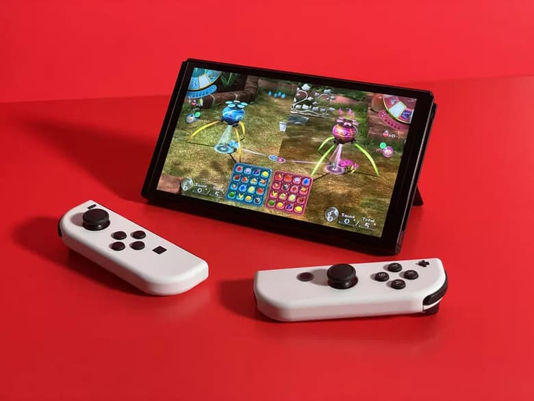 Nintendo Switch OLED sur son support, Joy-Con blancs détachés, sur fond rouge