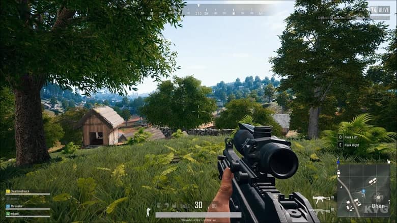 PUBG : un joueur vise à la lunette depuis les hautes herbes, une maison en ligne de mire
