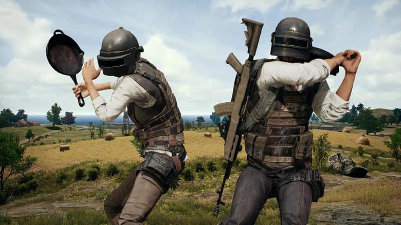 PUBG : deux joueurs casqués, l'un armé d'une poêle, dans un champ