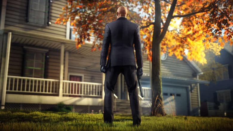 Hitman 3 : l'Agent 47 de dos devant un pavillon américain en automne