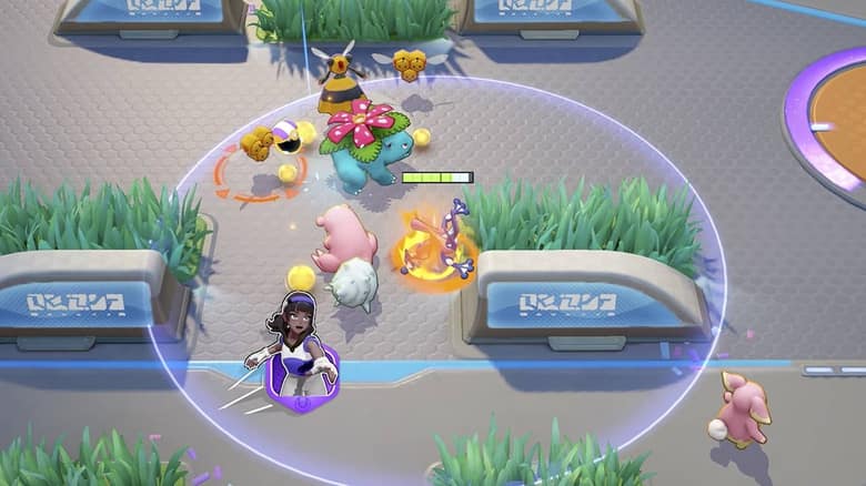 Florizarre au combat au milieu de Pokémon sauvages, avec des boules d'énergie jaunes au sol, sur un terrain de Pokémon UNITE