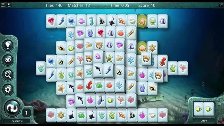Partie de Microsoft Mahjong avec des tuiles aux motifs marins, le compteur de tuiles restantes et les boutons d'indice, de mélange et d'annulation