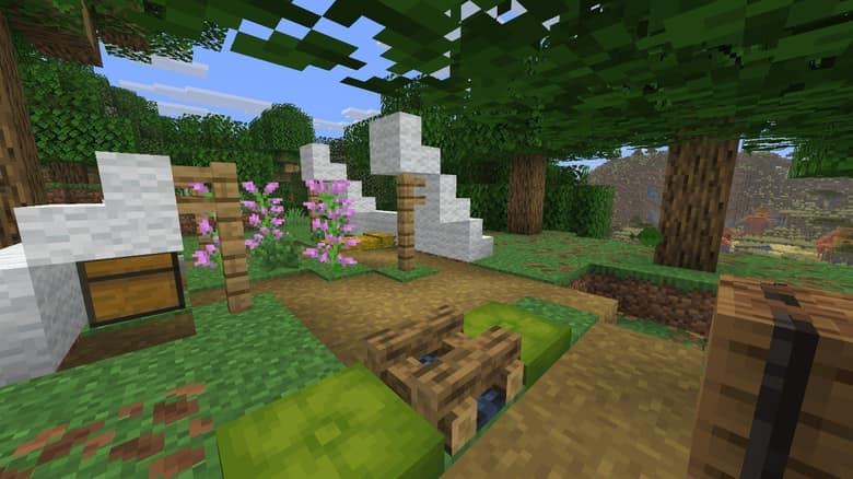 Un camp abandonné dans une forêt de Minecraft : des tentes en laine blanche, un coffre, des fleurs roses et un feu de camp éteint