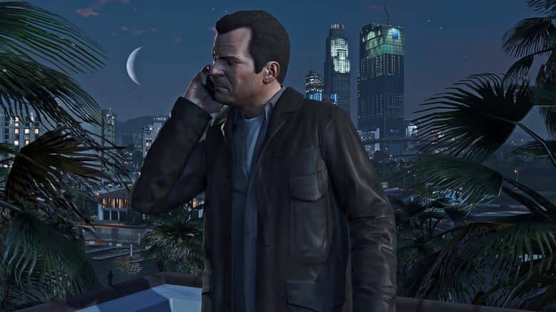 Michael, l'un des trois héros de GTA 5, parle au téléphone sur une terrasse la nuit, devant les gratte-ciel de Los Santos