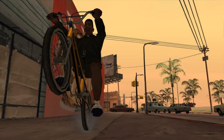 CJ fait une roue arrière à vélo sur un trottoir de Los Santos, au coucher du soleil