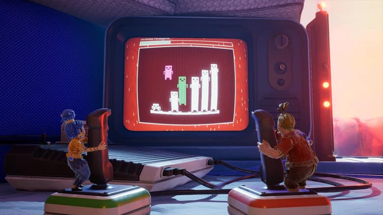 Cody et May manœuvrent deux joysticks géants devant un vieux téléviseur qui affiche un mini-jeu
