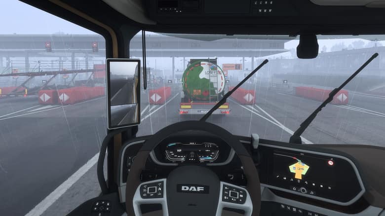 Vue depuis la cabine d'un camion DAF, avec le volant et le tableau de bord, à un péage sous la pluie
