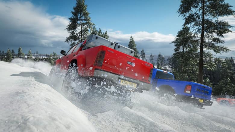Capture officielle de Forza Horizon 4 : deux pick-up, un rouge et un bleu, roulent dans la neige entre des sapins