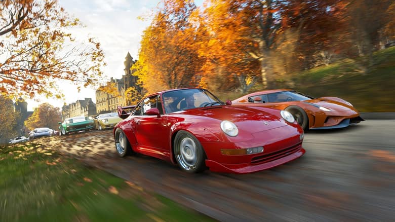 Capture officielle de Forza Horizon 4 : une Porsche rouge et une supercar orange roulent sur une route bordée d'arbres aux feuilles d'automne
