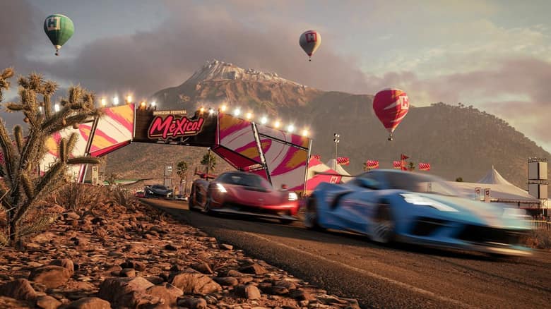 Capture officielle de Forza Horizon 5 : des voitures de sport passent sous l'arche colorée du festival Horizon, devant une montagne et des montgolfières