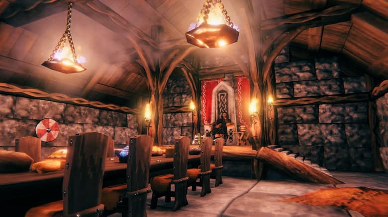 L'intérieur d'une grande maison viking en bois éclairée par des lustres, avec une longue table et un trône