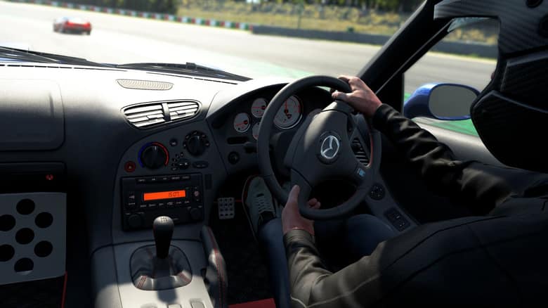 Vue depuis l'habitacle d'une Mazda, mains du pilote sur le volant, sur circuit