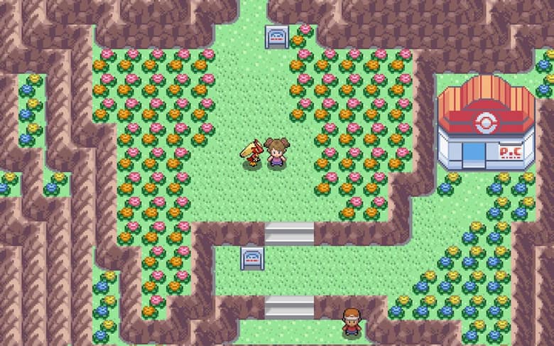 Un dresseur et son Pokémon sur une route bordée de fleurs, devant un Centre Pokémon, dans le style des jeux Game Boy Advance